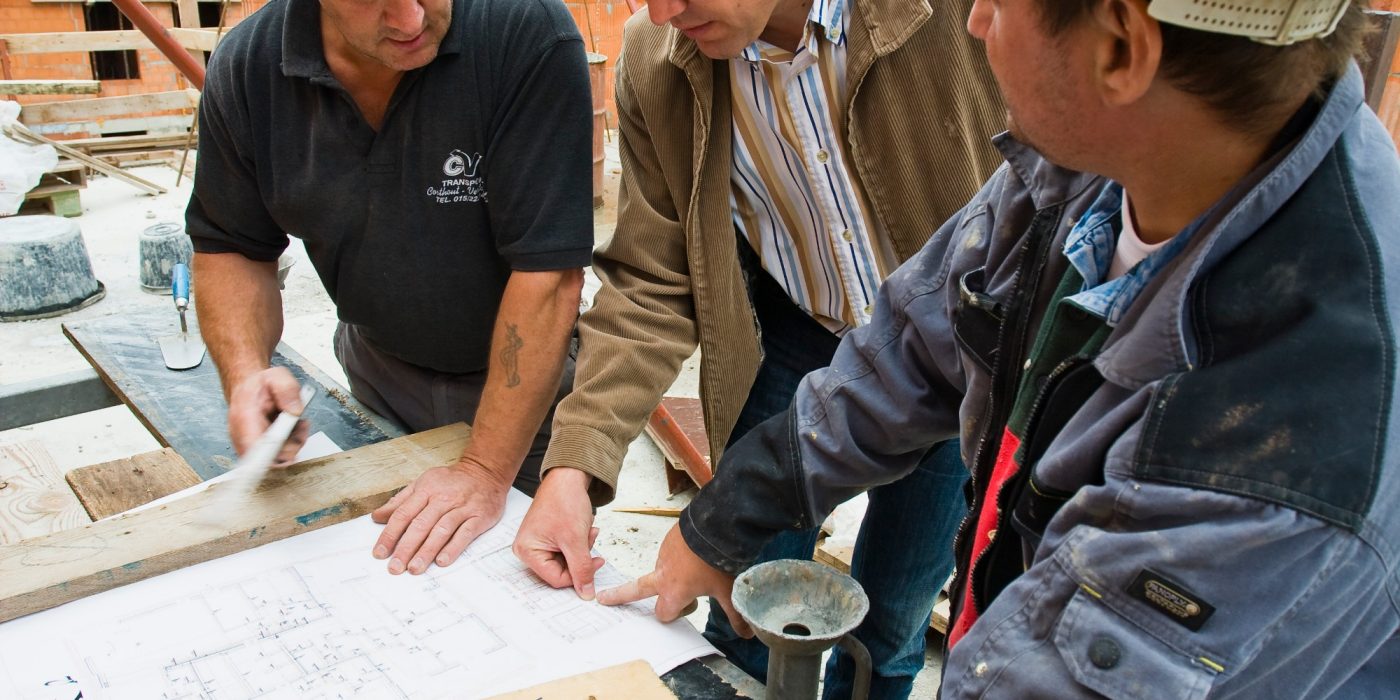 People discuss a construction plan on a yard 