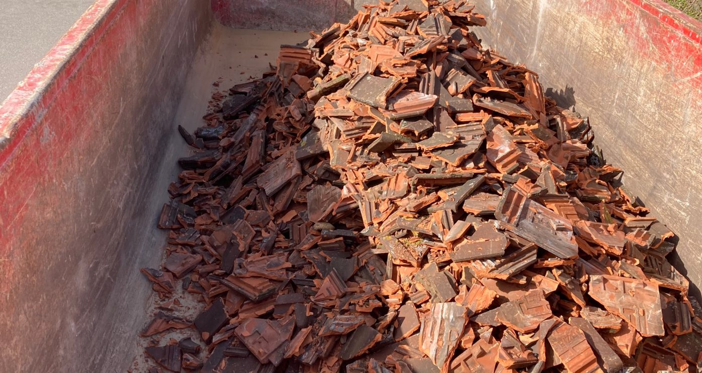 Conteneur rempli d’anciennes tuiles en terre cuite prêtes à être recyclées