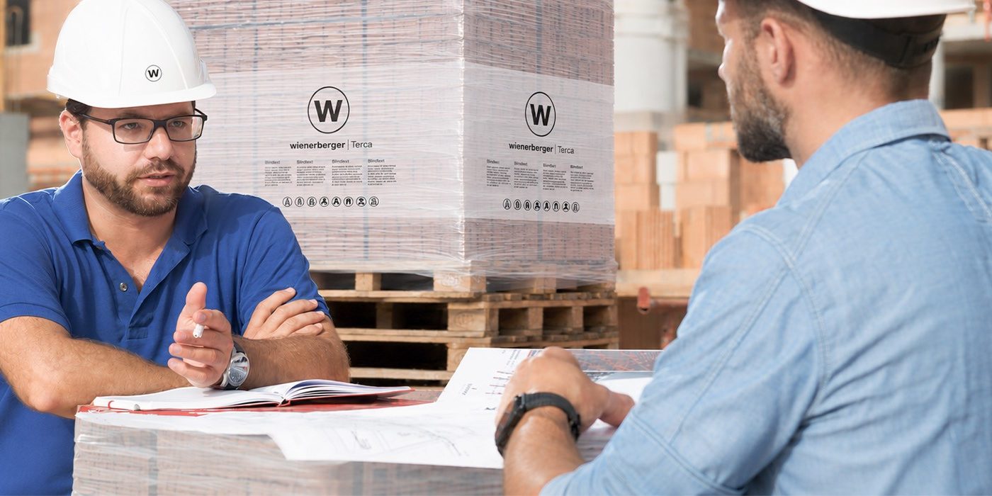 Des entrepreneurs en conversation sur le chantier en regardant les plans de la construction