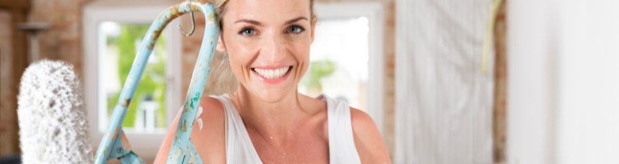 Smiling woman holding a cup next to a whitewashed wall