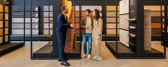 Toonzaalmedewerker in gesprek met bezoekers van de showroom in Londerzeel