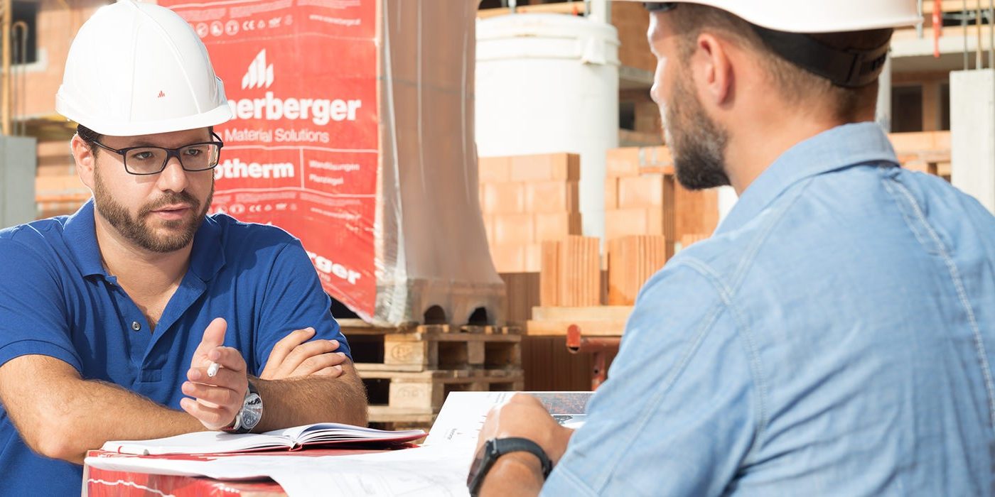 Aannemers voeren een gesprek op de werf waarbij de plannen worden bekeken